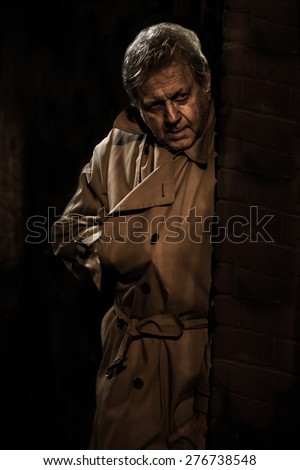 Assassin - Russian Spy - Man with Hand in Trench Coat - Creepy Killer Lurking in Doorway - Dangerous Hitman in Shadows - Stranger with Gun - Noir Style Secret Agent. Vintage noise effect.