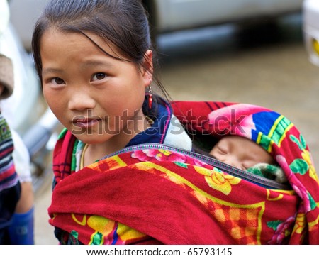 SAPA, VIETNAM - NOV 22: Unidentified young girl of the Black H\'Mong Ethnic Minority People carries baby on November 22, 2010 in Sapa, Vietnam.  H\'Mong are the 9th largest ethnic group in Vietnam.