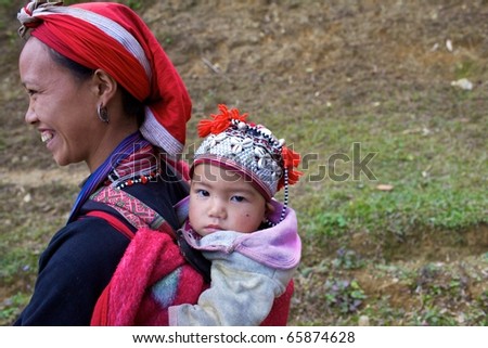 SAPA, VIETNAM - NOV 22: Unidentified young girl from the Red Dao Ethnic Minority People carrying baby on November 22, 2010 in Sapa, Vietnam.  Red Dao are the 9th largest ethnic group in Vietnam