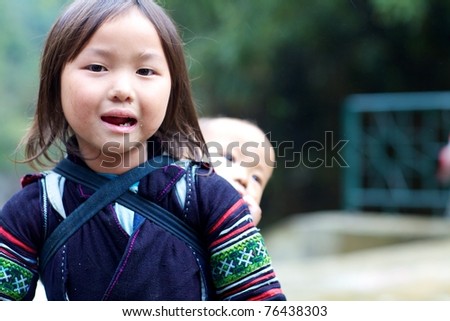 SAPA, VIETNAM, NOVEMBER 22: Unidentified young girl of the Black H'mong Ethnic Minority People carrying baby in Sapa, Vietnam on November 22, 2010. H'mong are the 8th largest ethnic group in Vietnam