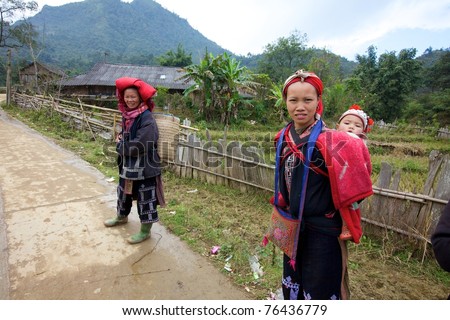 SAPA, VIETNAM - NOV 22: Unidentified young girl from the Red Dao Ethnic Minority people carrying baby on November 22, 2010 in Sapa, Vietnam. Red Dao are the 9th largest ethnic group in Vietnam