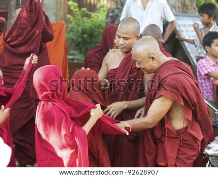 BAGAN, MYANMAR: OCT 14: Two adult monks helping novice monks to put on their traditional red robes in Bagan, Myanmar on October 14, 2011. Eighty nine percent of the Burmese population is Buddhist.