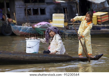 SIEM REAP, CAMBODIA - JAN 23: Woman and child rowing rowing boat on Tonle Sap Lake in Siem Reap, Cambodia on January 23, 2012. Tonle Sap is the largest freshwater lake in SE Asia peaking at 16k km2