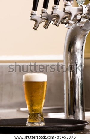 glass of beer on a tray with the beer tap above