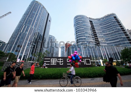 BEIJING-MAY 12: People walk and cycle around Sanlitun SOHO, a five shopping malls and nine office/apartment buildings designed by Japanese architect Kengo Kuma, on May 12, 2012 in Beijing, China.