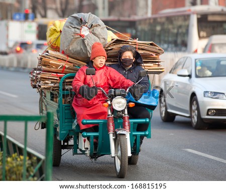 BEIJING,CHINA-DEC 25,2013: People is seen on a freight bike loaded with goods and material.  China\'s Green Fence quality controls have slow down investments among recycling industries worldwide