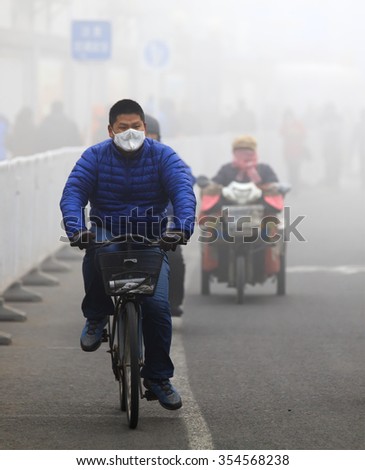 BEIJING, CHINA - DECEMBER 23, 2015: An unidentified man ride a bicycle in smog, in a foggy and hazy day. Beijing issued a red alert for air pollution on Friday, its second red alert this month.