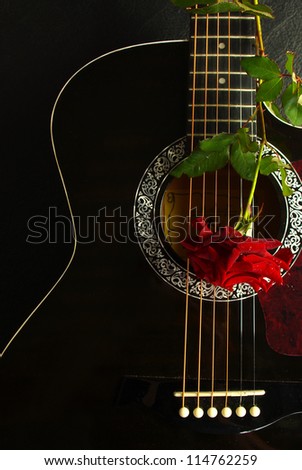 Red rose on a black acoustic guitar .Vertical.Can be used as a nice background, album cover. Dark colors, contrast