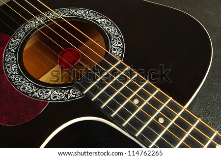 Acoustic black guitar closeup - includes strings, fingerboard and part of the body