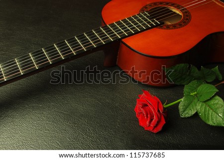 Classic guitar and red rose. Black background