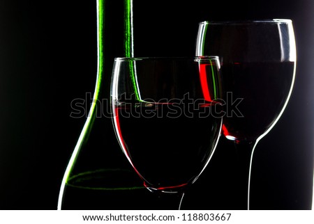 Two glasses of  red wine, one bottle. Close up. Black background