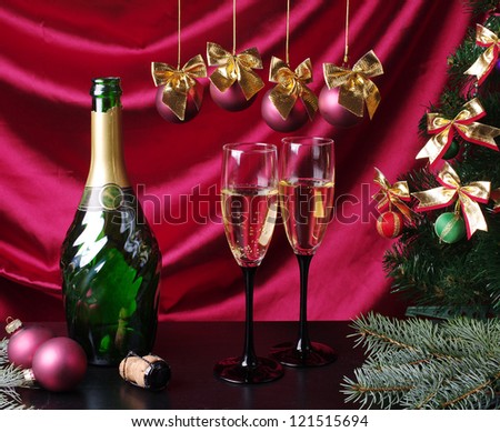 One bottle  and  two  goblets of champagne with new year decorations against purple drapery. Happy New Year!