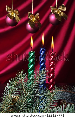 Three color candles  and new year balls against purple drapery