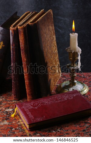 Note-book, three books and burning candle