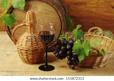 Still life with wine bottles, one glass of red wine, grapes  and oak barrel