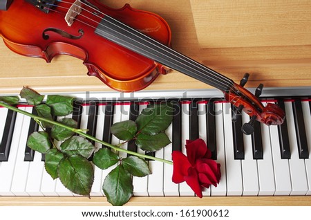 Piano keyboard, red rose and violin
