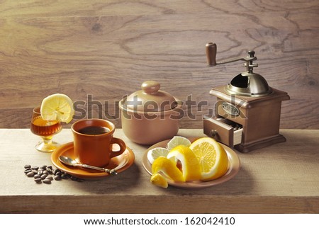 Coffee and cognac. Cup of coffee, glass of cognac, coffeepot, grains and lemon on the table