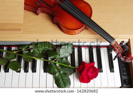 Piano keyboard, red rose and violin
