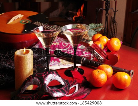 Colorful Venice masks, two glasses of wine, fruits, burning candle
