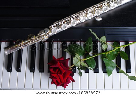 Piano keyboard and flute and red rose close-up