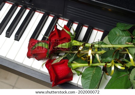 Three red roses on a piano keyboard