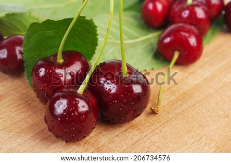 Sweet cherries with water drops on wooden table