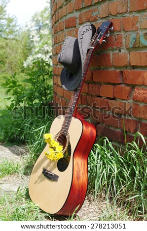 Guitar and cowboy hat near the brick wall