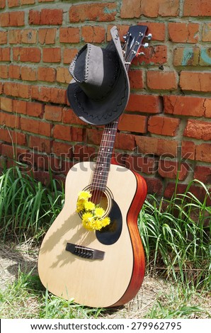 Acoustic guitar and cowboys hat in front of  the brick wall