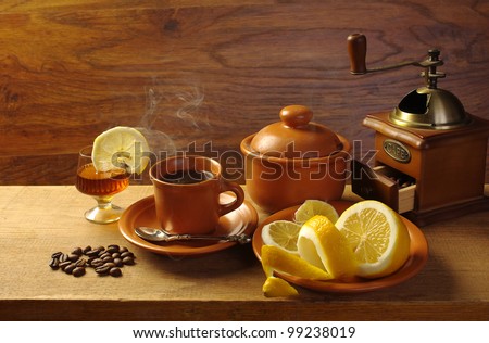 Coffee and cognac. Cup of coffee, glass of cognac, coffeepot, grains and lemon on the table