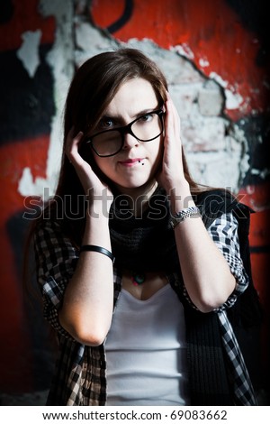 Clumsy punk rock girl with nerdy glasses  in front of graffiti