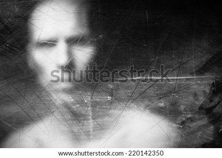 Blurry human face behind dusty scratched glass