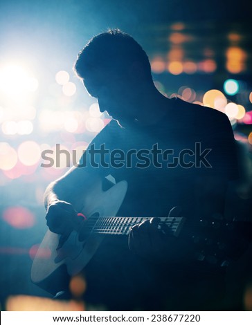 Guitarist playing acoustic guitar. Unplugged performance in the dark.