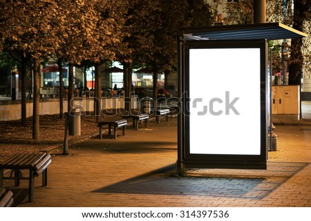 Blank bus stop advertising billboard in the city at night.