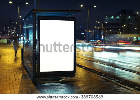 Blank bus stop advertising billboard in the city at night.