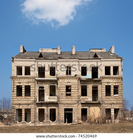 Abandoned damaged old house against blue cloudy sky