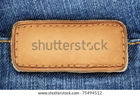 Blank leather jeans label sewed on a blue jeans. Can be used as background for your text.