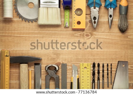 Working tools on a wooden boards background. Including saw, ruler, drill, nails, pliers,hammer, brush,thread,chisel and other.