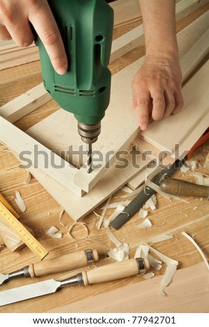 Wooden workshop table with tools. Man\'s arms drill plank.