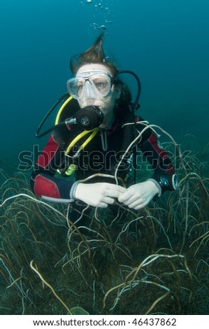 young female scuba diver swimming over coral