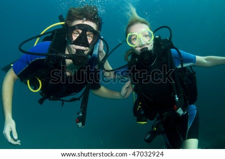 boy and girl scuba dive together in clear blue water