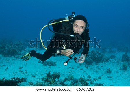scuba diver takes her mask off underwater