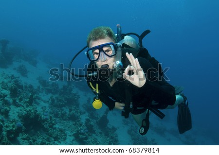 Male scuba diver gives OK sign in clear blue water
