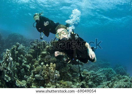 mother and son scuba dive together om beautiful coral reef