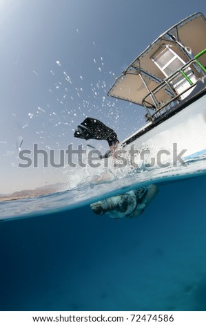 Scuba diver enters the water, over under shot of boat and ocean
