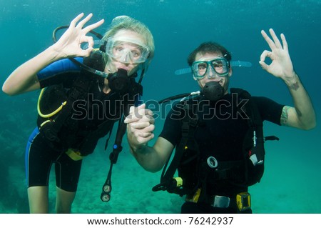 couple scuba dive together in the ocean