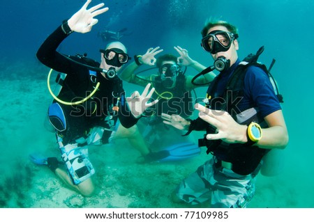 Scuba Divers all give OK signs and are very happy