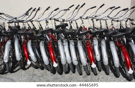 Row of bicycles in Munich, Germany. The bikes are cruisers with wide handlebars and the mudguards are red and silver