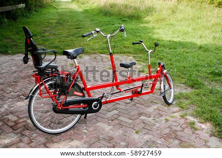 Red tandem bike with child\'s seat