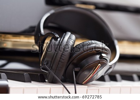 Modern headphones on keyboard of classic black grand piano