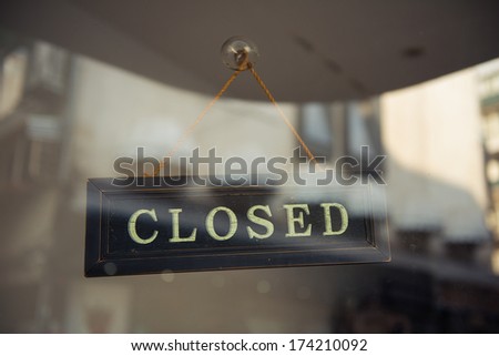 A close up of a \'CLOSED\' sign hanging in a window
